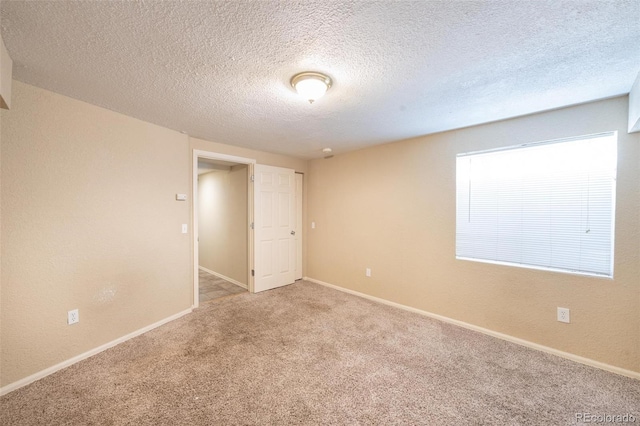 unfurnished room featuring carpet flooring and a textured ceiling