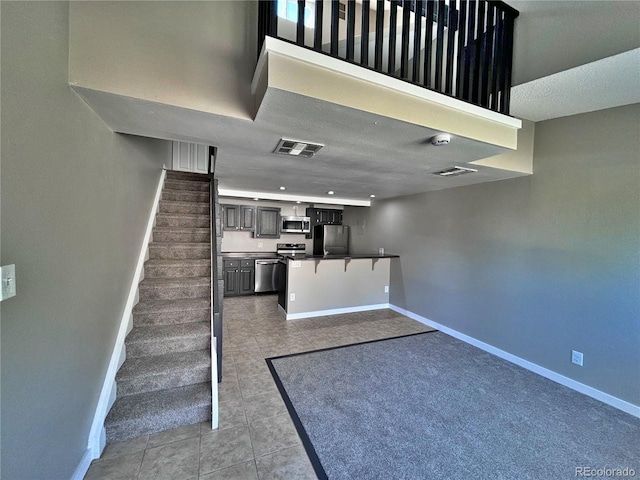 kitchen featuring kitchen peninsula, appliances with stainless steel finishes, a kitchen bar, and light tile patterned floors