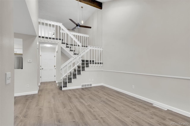 14243 E Radcliff Cir, Aurora, CO 80015 - unfurnished living room featuring stairway, wood finished floors, beam ceiling, high vaulted ceiling, and a ceiling fan