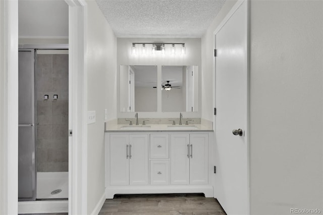 14243 E Radcliff Cir, Aurora, CO 80015 - full bathroom featuring double vanity, a stall shower, wood finished floors, a textured ceiling, and ceiling fan