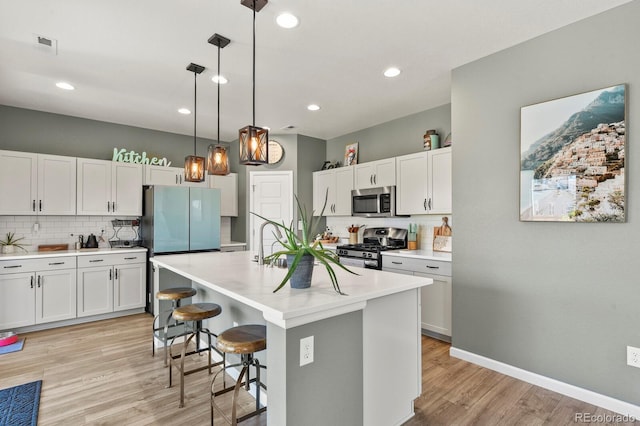 27893 E 6th Pl, Aurora, CO 80018 - kitchen with stainless steel appliances, decorative backsplash, a breakfast bar, light wood-style flooring, and light countertops