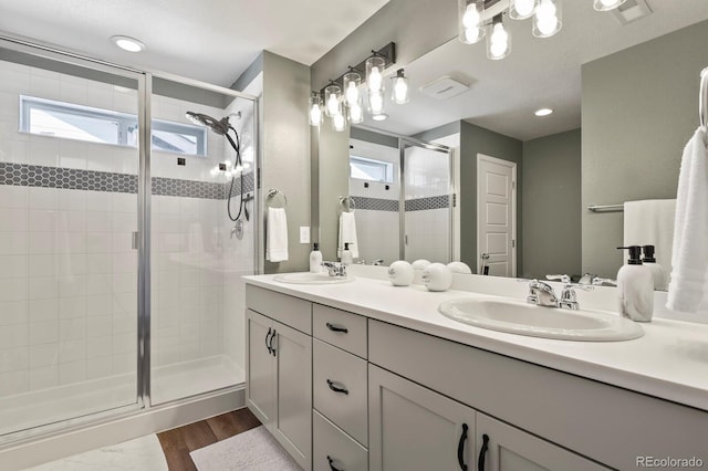 27893 E 6th Pl, Aurora, CO 80018 - bathroom with double vanity, a stall shower, plenty of natural light, and wood finished floors