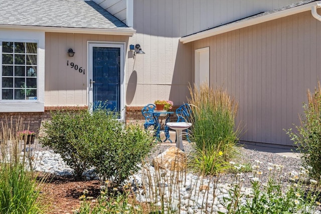 19061 E Oxford Dr, Aurora, CO 80013 - view of exterior entry with roof with shingles, brick siding, and a patio