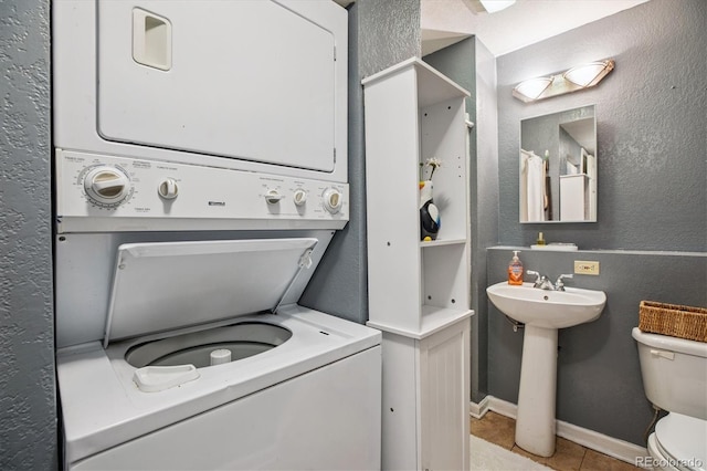 19061 E Oxford Dr, Aurora, CO 80013 - washroom featuring stacked washer and clothes dryer, light tile patterned floors, and a textured wall