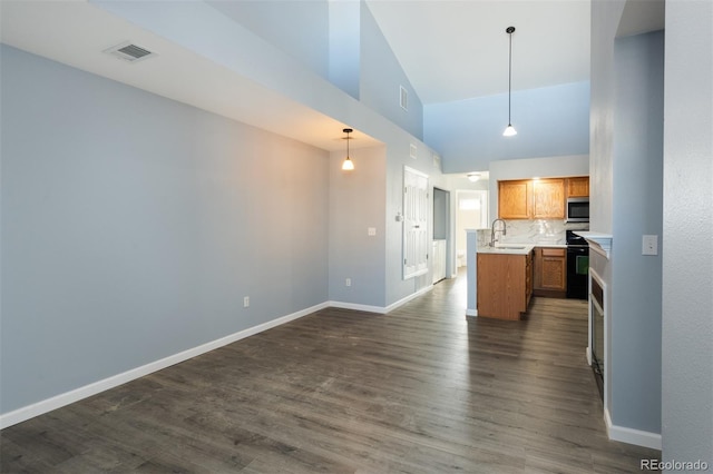 kitchen featuring electric range, dark wood-type flooring, hanging light fixtures, tasteful backsplash, and high vaulted ceiling