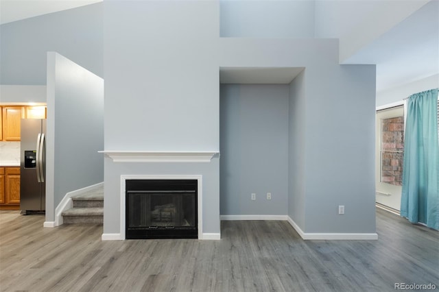 unfurnished living room with light hardwood / wood-style floors and high vaulted ceiling