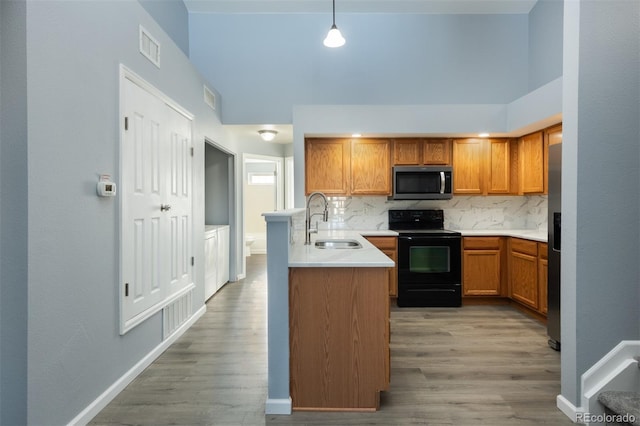 kitchen with backsplash, sink, hanging light fixtures, light hardwood / wood-style flooring, and stainless steel appliances