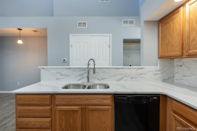 kitchen with sink, black dishwasher, light stone counters, pendant lighting, and hardwood / wood-style flooring