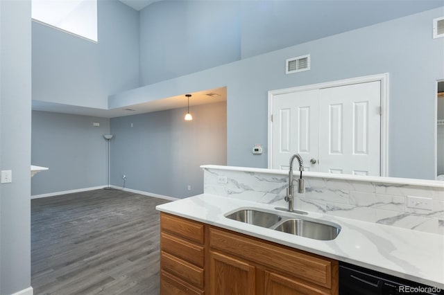 kitchen with dishwasher, sink, dark wood-type flooring, hanging light fixtures, and a high ceiling