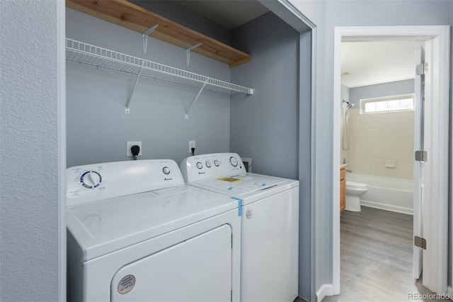 laundry room with light wood-type flooring and washing machine and dryer