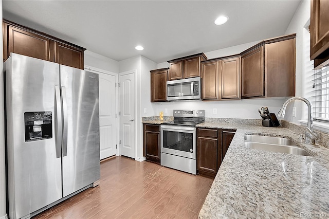 6626 Mandan Dr, Colorado Springs, CO 80925 - kitchen with wood finished floors, dark brown cabinetry, light stone countertops, a sink, and appliances with stainless steel finishes