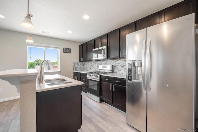 1732 Aspen Meadows Cir, Federal Heights, CO 80260 - kitchen with stainless steel appliances, light wood finished floors, tasteful backsplash, light countertops, and decorative light fixtures