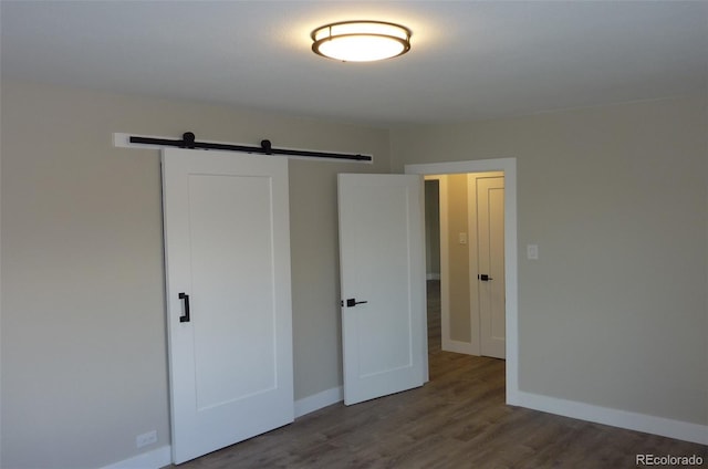 3575 W 9th Ave, Denver, CO 80204 - unfurnished bedroom featuring a barn door, a closet, and wood finished floors
