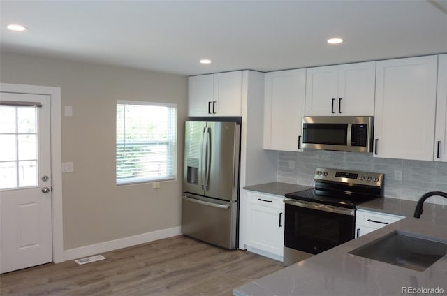 3575 W 9th Ave, Denver, CO 80204 - kitchen with appliances with stainless steel finishes, light wood finished floors, white cabinets, decorative backsplash, and recessed lighting