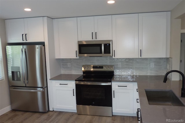 3575 W 9th Ave, Denver, CO 80204 - kitchen featuring appliances with stainless steel finishes, wood finished floors, white cabinets, backsplash, and recessed lighting