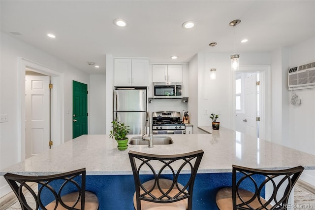 kitchen featuring stainless steel appliances, white cabinetry, a breakfast bar, and decorative light fixtures