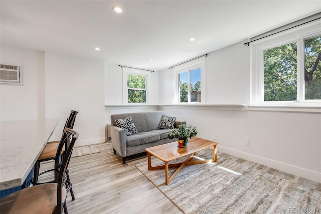 living room featuring a healthy amount of sunlight, light hardwood / wood-style floors, and an AC wall unit