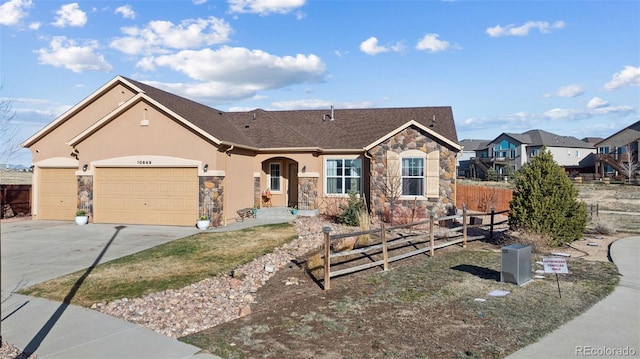 10649 Mt Emerald Dr, Peyton, CO 80831 - view of front of home with stone siding, driveway, fence, an attached garage, and stucco siding
