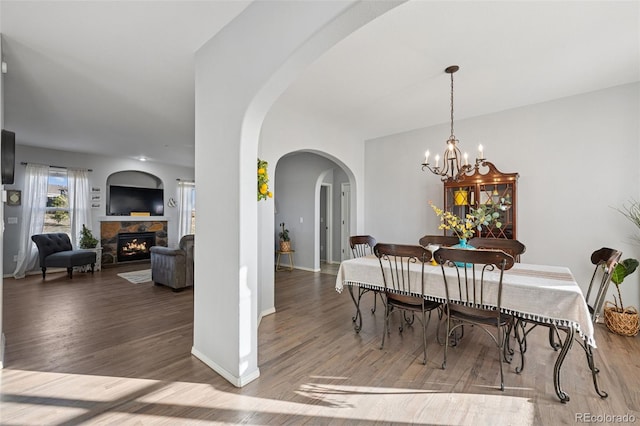 10649 Mt Emerald Dr, Peyton, CO 80831 - dining area featuring arched walkways, wood finished floors, a fireplace, a chandelier, and baseboards