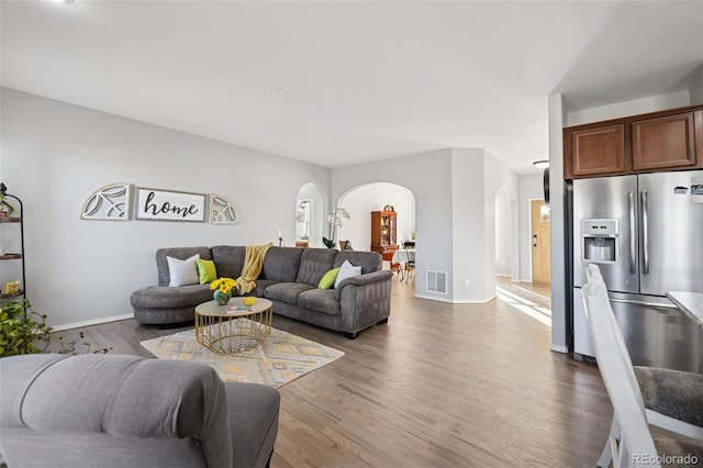 10649 Mt Emerald Dr, Peyton, CO 80831 - living room featuring arched walkways, wood finished floors, and baseboards
