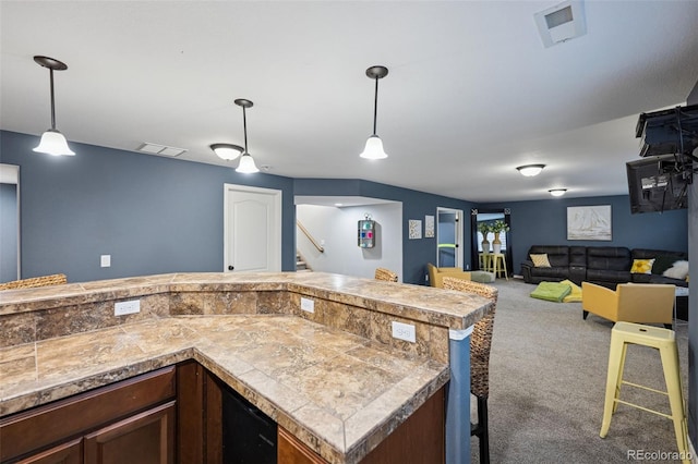 10649 Mt Emerald Dr, Peyton, CO 80831 - kitchen with tile countertops, carpet floors, hanging light fixtures, open floor plan, and dark brown cabinetry