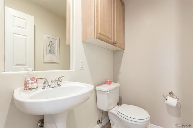 bathroom featuring baseboards, a sink, and toilet