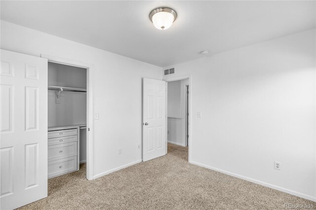 unfurnished bedroom with a closet and light colored carpet