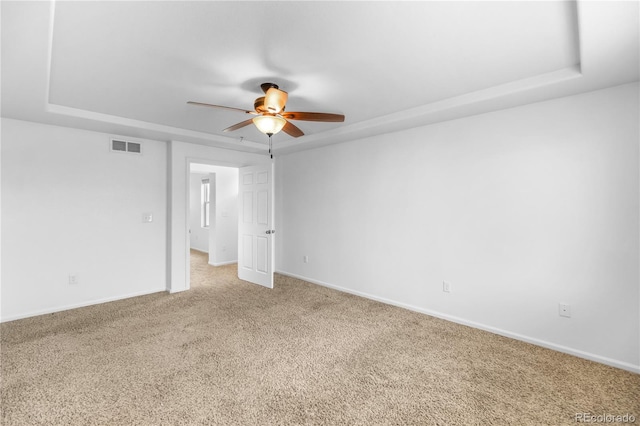 empty room featuring carpet flooring, ceiling fan, and a raised ceiling