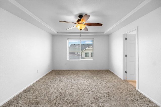 empty room featuring a tray ceiling, ceiling fan, and light colored carpet