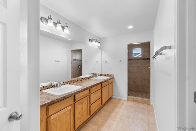 bathroom featuring tiled shower, vanity, and tile patterned flooring