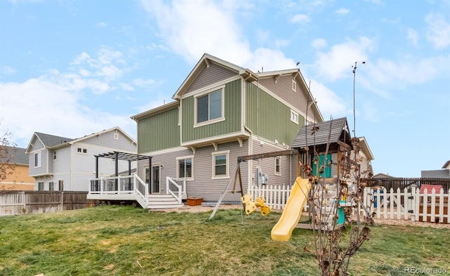 back of property with a yard, a playground, and a deck