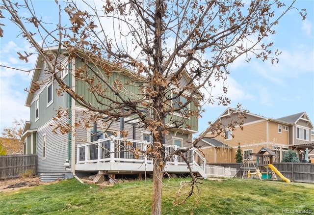 rear view of property featuring a playground, a deck, and a yard