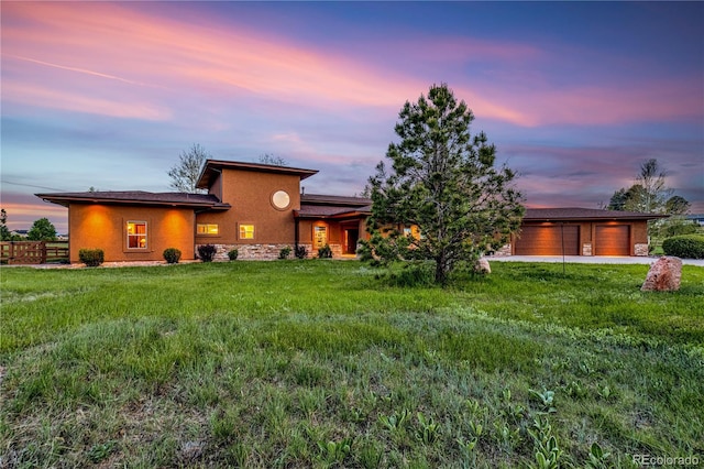 17595 Black Forest Rd, Colorado Springs, CO 80908 - back of house at dusk featuring a garage, stucco siding, and stone siding