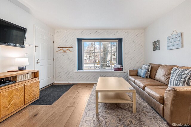 living room with wallpapered walls, baseboards, and wood finished floors