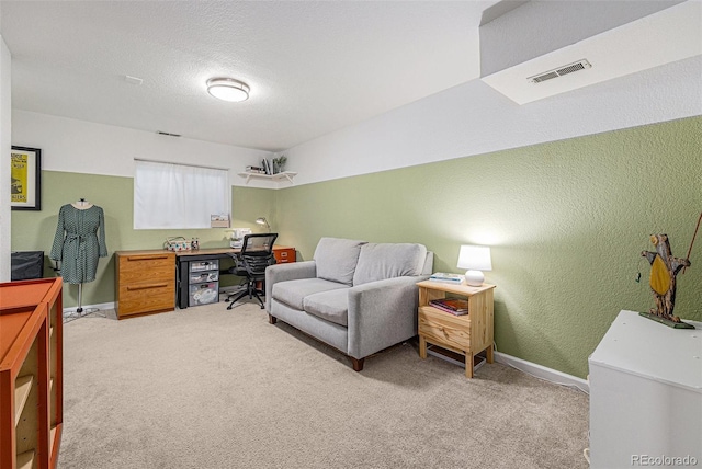 office with visible vents, a textured wall, light carpet, and baseboards