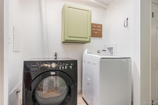 laundry room featuring light wood finished floors, washer and clothes dryer, and cabinet space