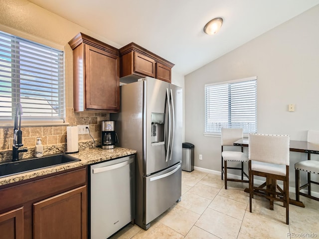 kitchen with vaulted ceiling, stainless steel appliances, decorative backsplash, sink, and light tile patterned flooring