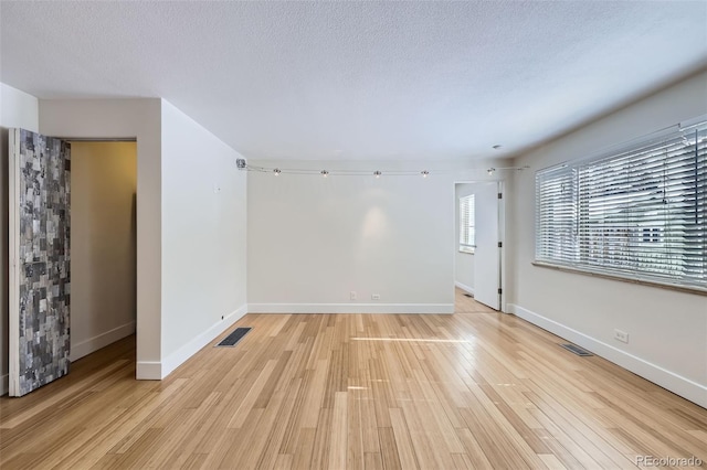 unfurnished room with a textured ceiling and light hardwood / wood-style floors