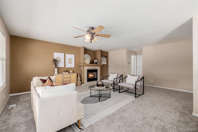 carpeted living room with visible vents, baseboards, ceiling fan, and a tile fireplace