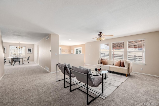 living area with visible vents, carpet floors, baseboards, and ceiling fan with notable chandelier