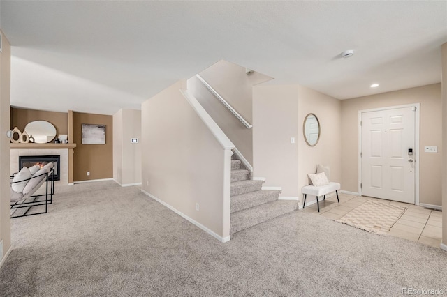 carpeted entrance foyer featuring tile patterned flooring, stairs, a fireplace, and baseboards