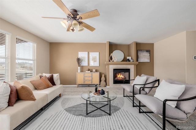 living room with baseboards, a tile fireplace, a ceiling fan, and carpet