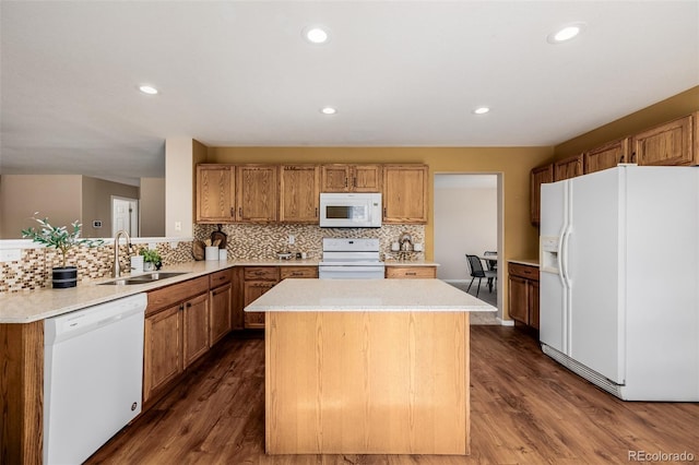 kitchen with white appliances, a kitchen island, dark wood-style flooring, and a sink