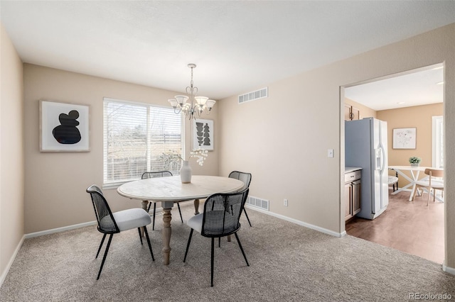 dining space with visible vents, baseboards, light carpet, and a chandelier