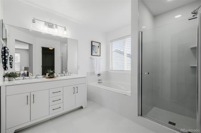 bathroom with a bath, a sink, a stall shower, and double vanity