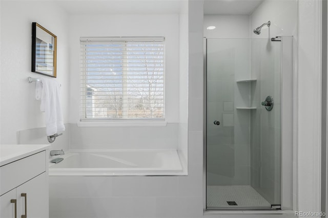 full bathroom featuring a stall shower, vanity, and a garden tub