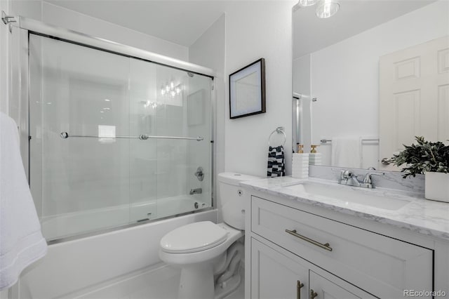 bathroom with combined bath / shower with glass door, toilet, and vanity