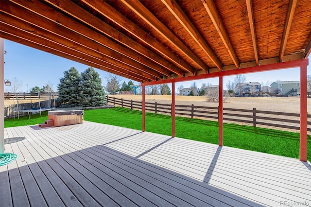 wooden deck featuring a trampoline, a fenced backyard, and a yard