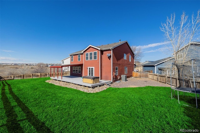 back of house with central AC unit, a trampoline, a fenced backyard, and a lawn