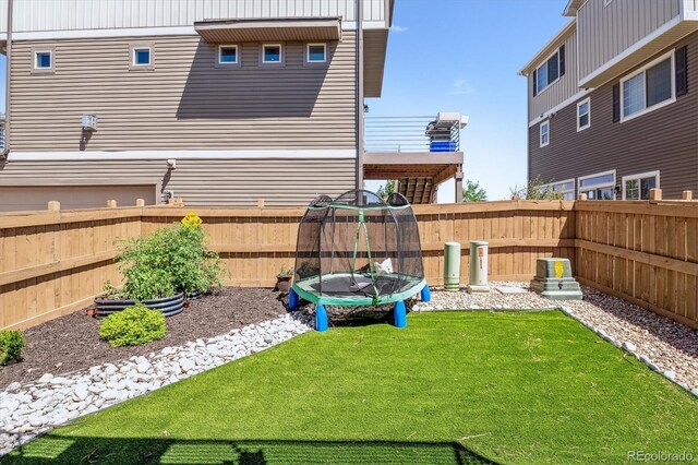 view of yard with a trampoline and a fenced backyard